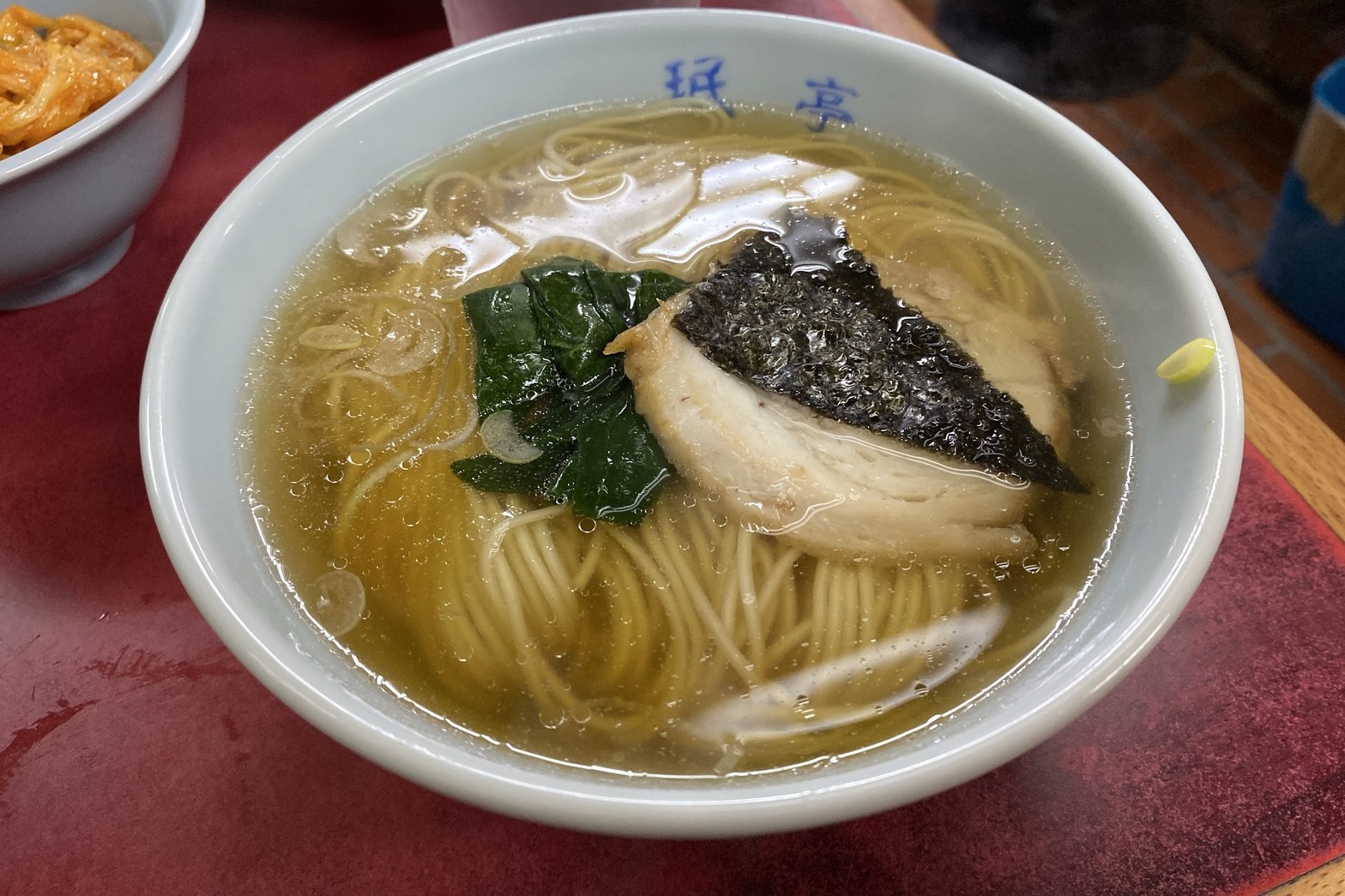 珉亭ロゴ入り白い丼に澄んだ醤油スープ、細麺・チャーシュー・海苔・ほうれん草が入ったラーメン