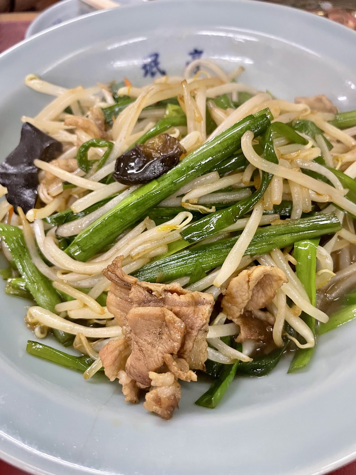 白い大皿にもやし・ニラ・豚肉・きくらげを炒め合わせた野菜炒め