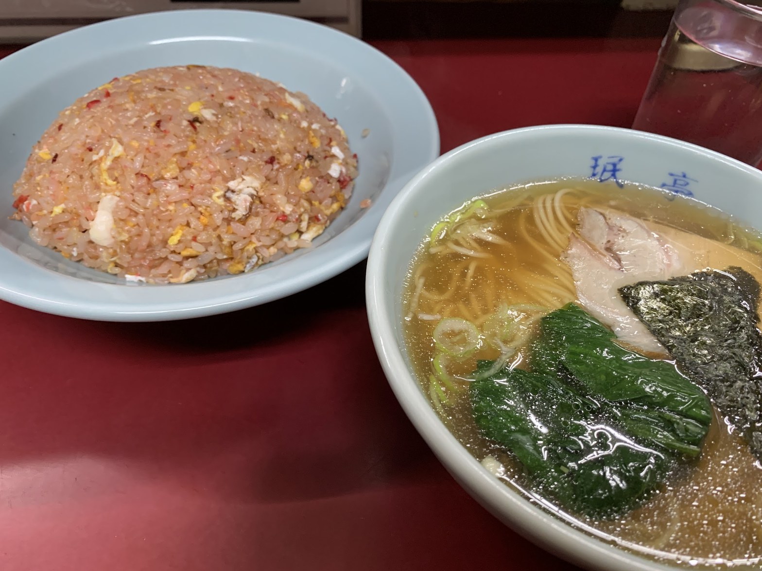 赤テーブルに並ぶ淡青色の皿のピンクチャーハンと珉亭ロゴ入り丼の醤油ラーメン